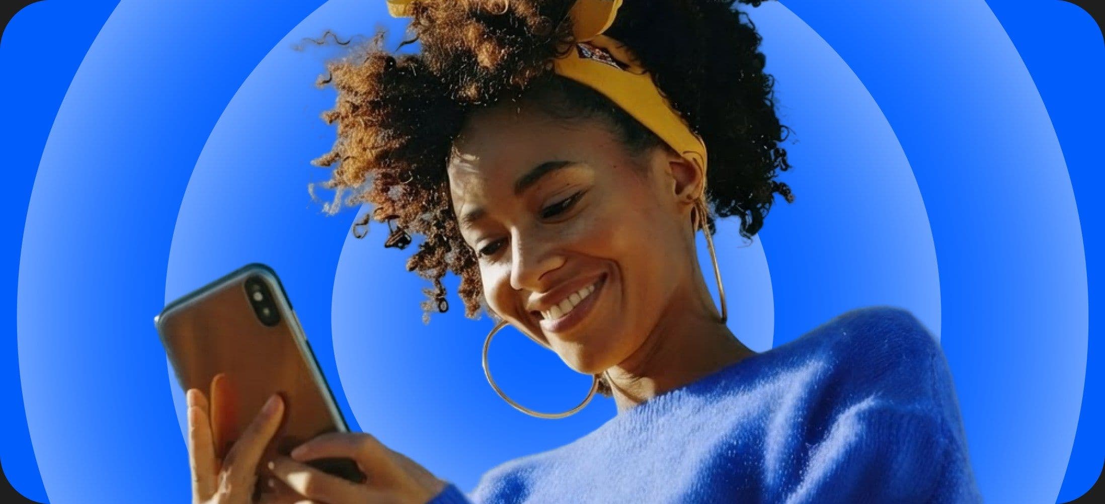 A student sitting on the floor looking at a phone
