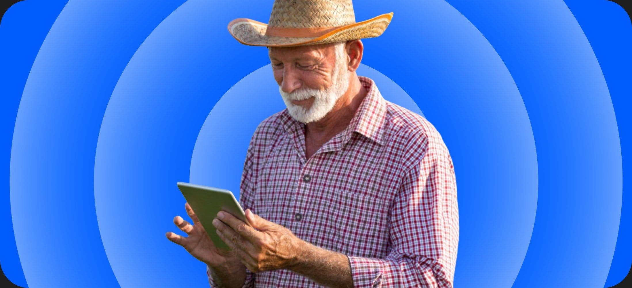 A man in a wide-brimmed hat using a tablet outdoors