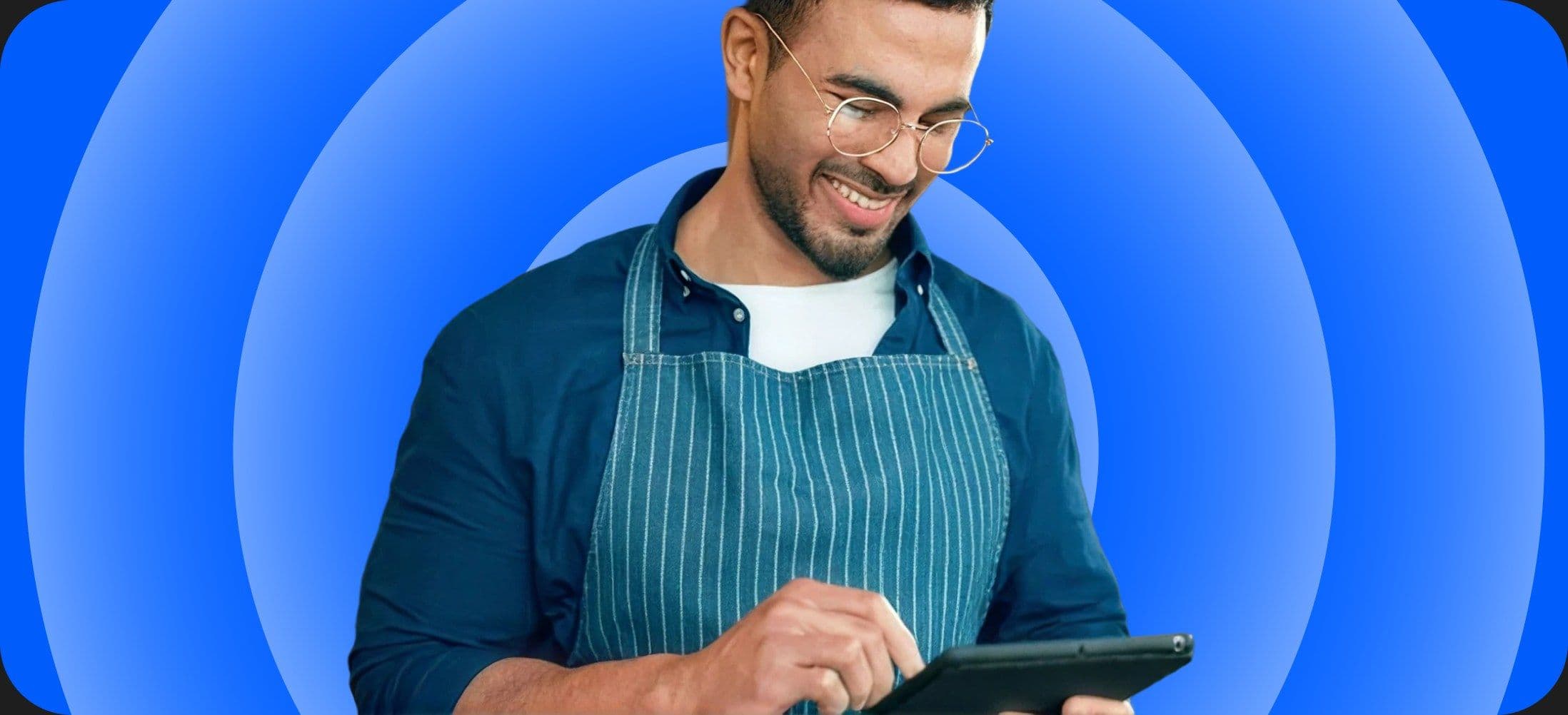 A small business owner in an apron using a tablet