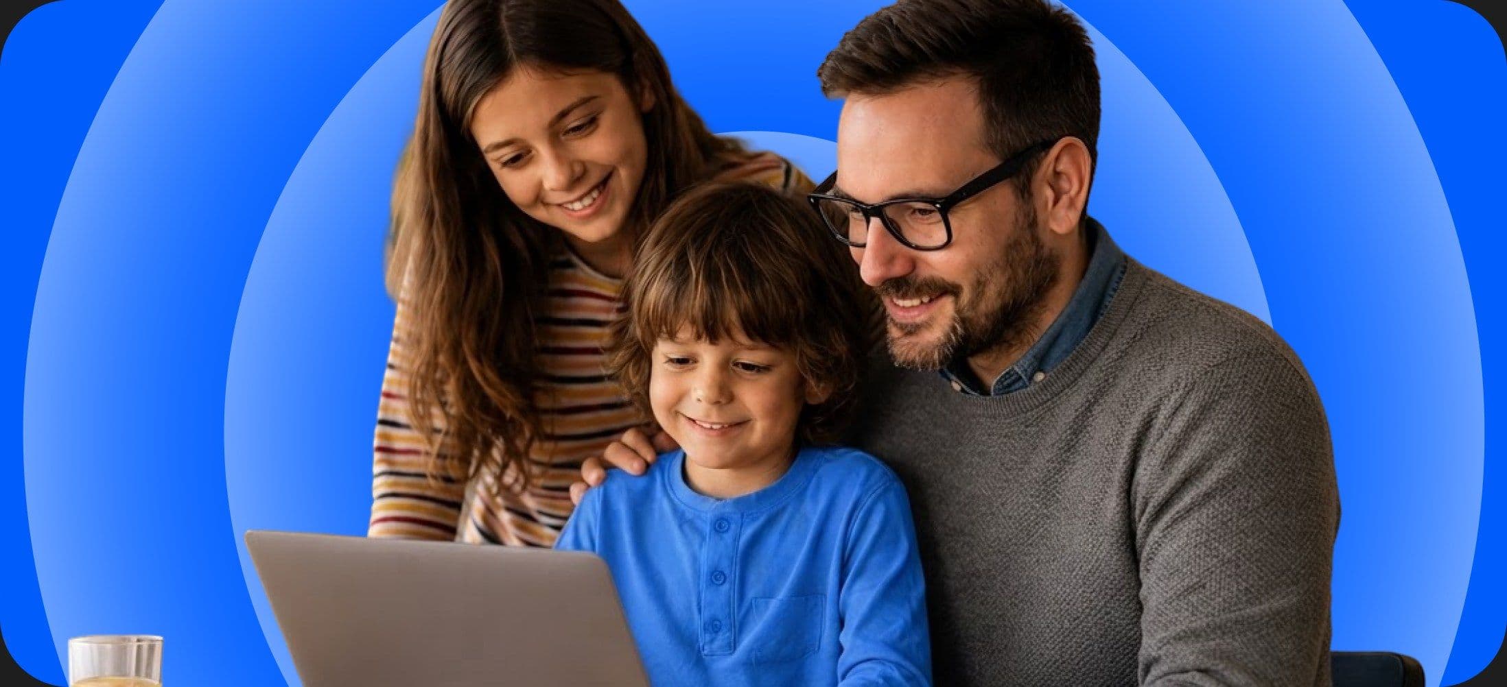 A family gathered around a laptop at a kitchen table